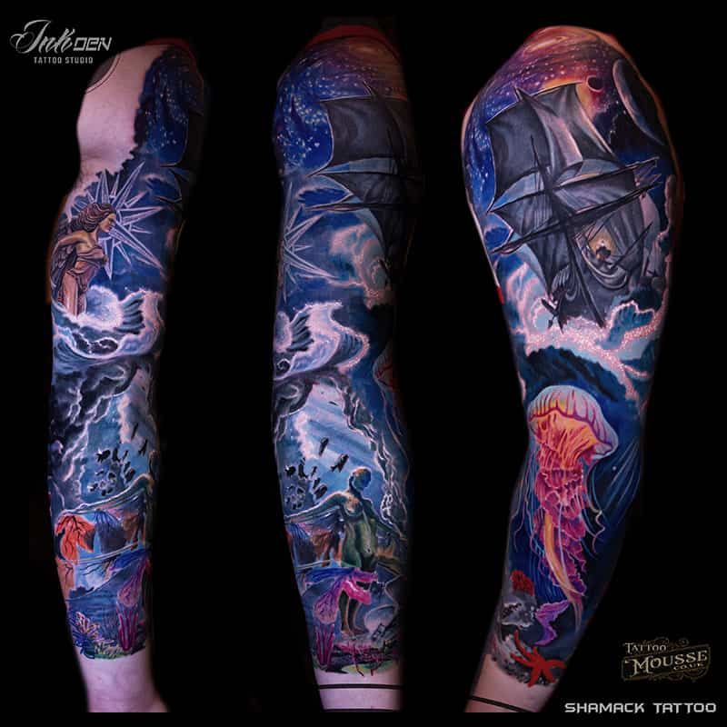 Three tattooed arm views with dark blue, pink, and purple ocean-themed artwork on black background