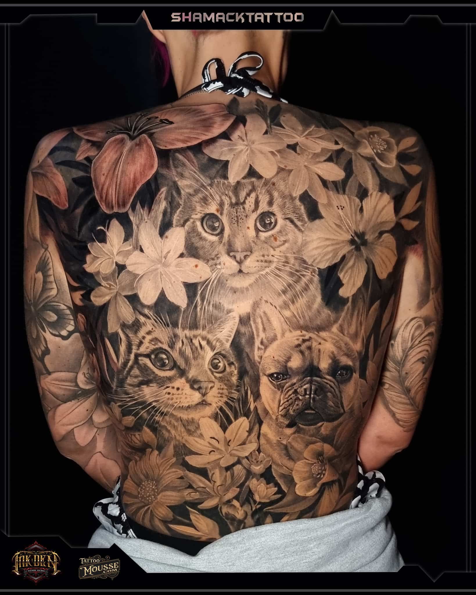 Back tattoo of three wolf faces framed by leaves, with floral and animal sleeve tattoos on the arms