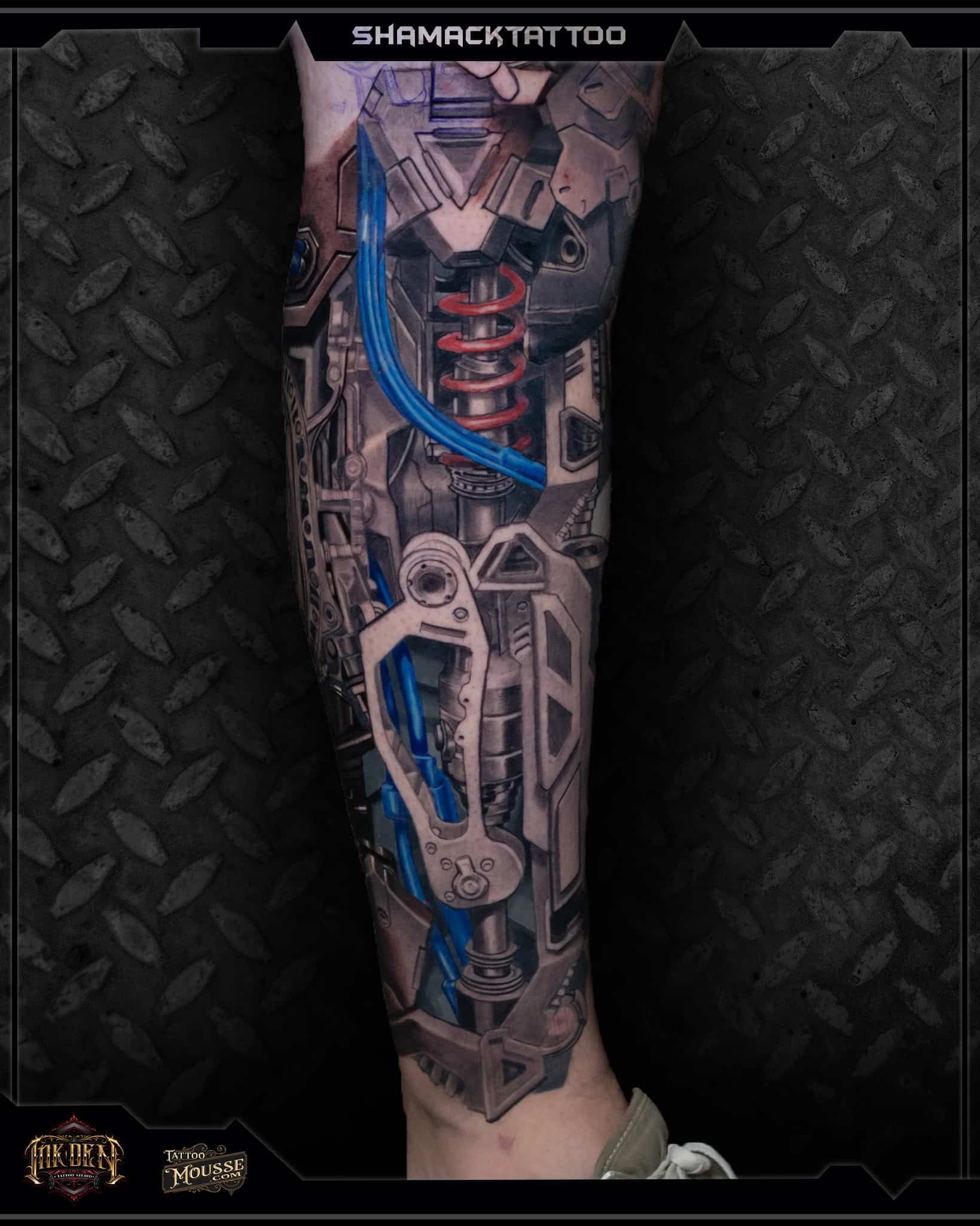 Lower leg tattoo with red coil and blue accents on dark geometric background