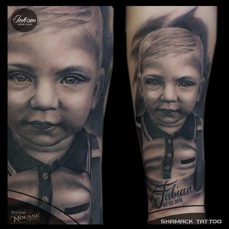 Portrait-style black and gray tattoo of a child’s face on a forearm, with name script below.